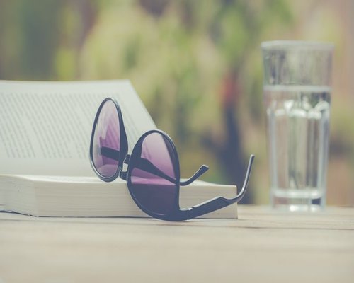 Glass of water next to an open book on a wooden table